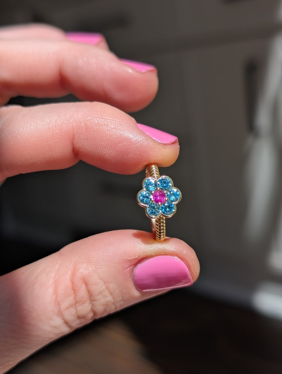 Blooms Medium Ring in blue zircon and pink ruby, close-up held in hand
