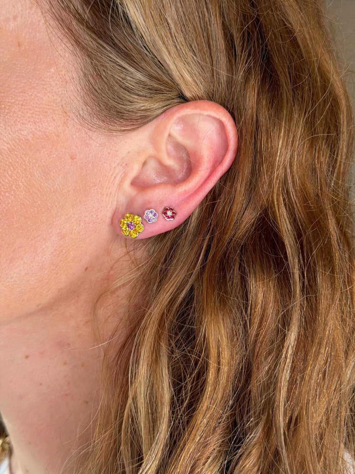 Blooms Stud Earring in yellow sapphire and grape garnet worn on the ear, stacked with Blooms Mini Studs