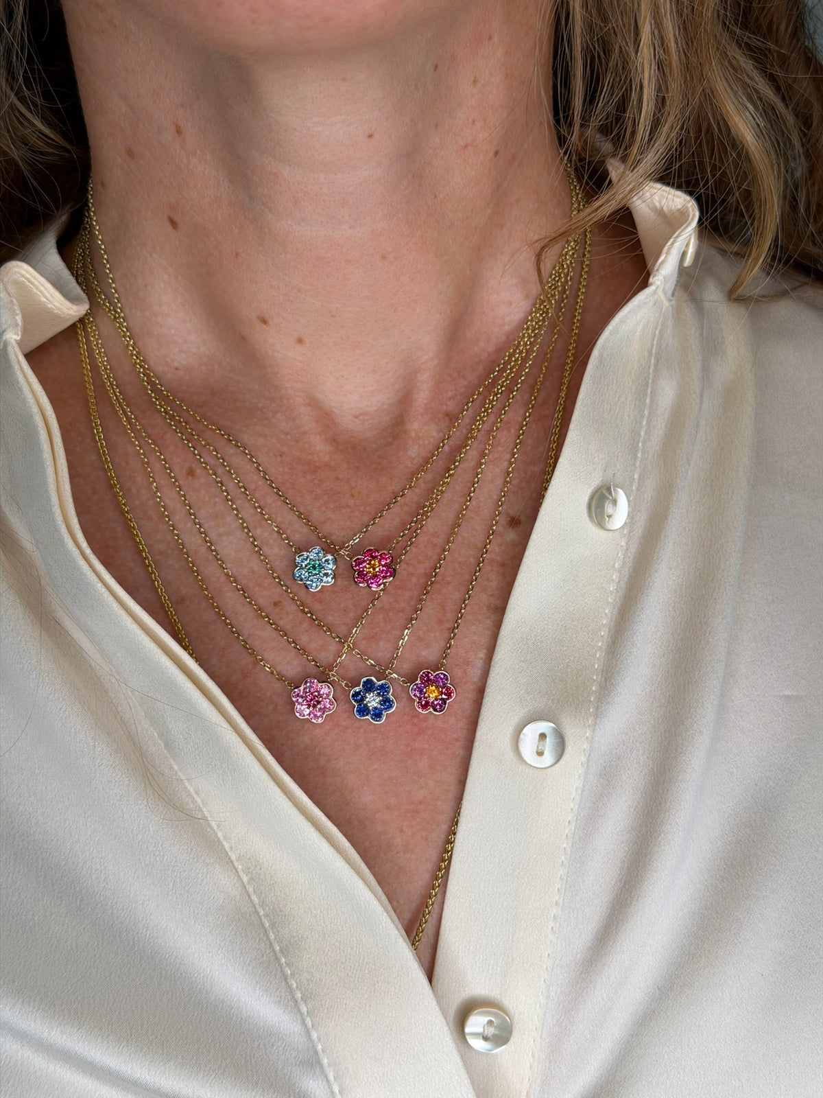Five Small Blooms Pendant Necklaces layered on the neck, close-up