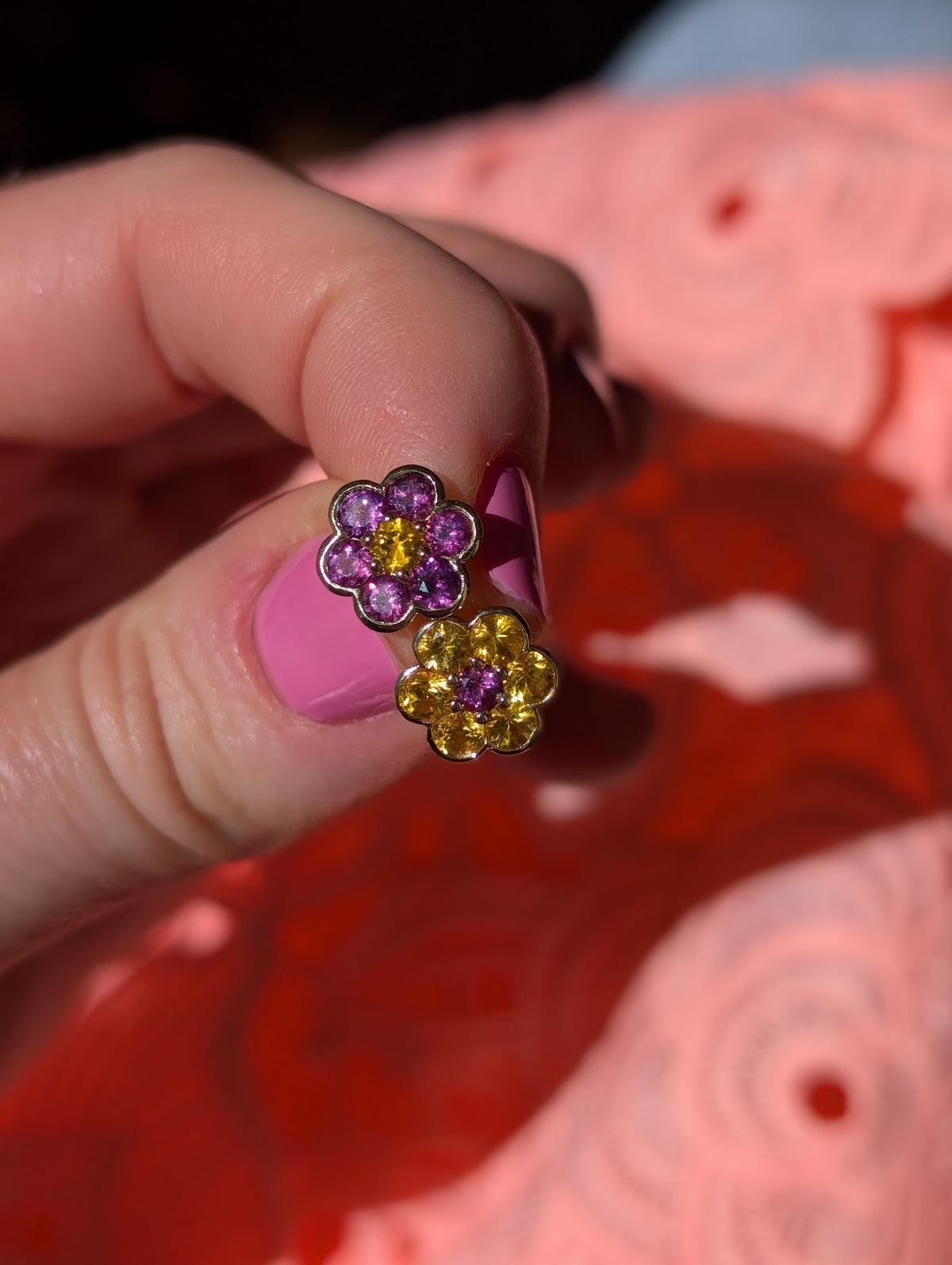 Blooms Stud Earrings in yellow sapphire and grape garnet, opposite flowers, pair held in hand