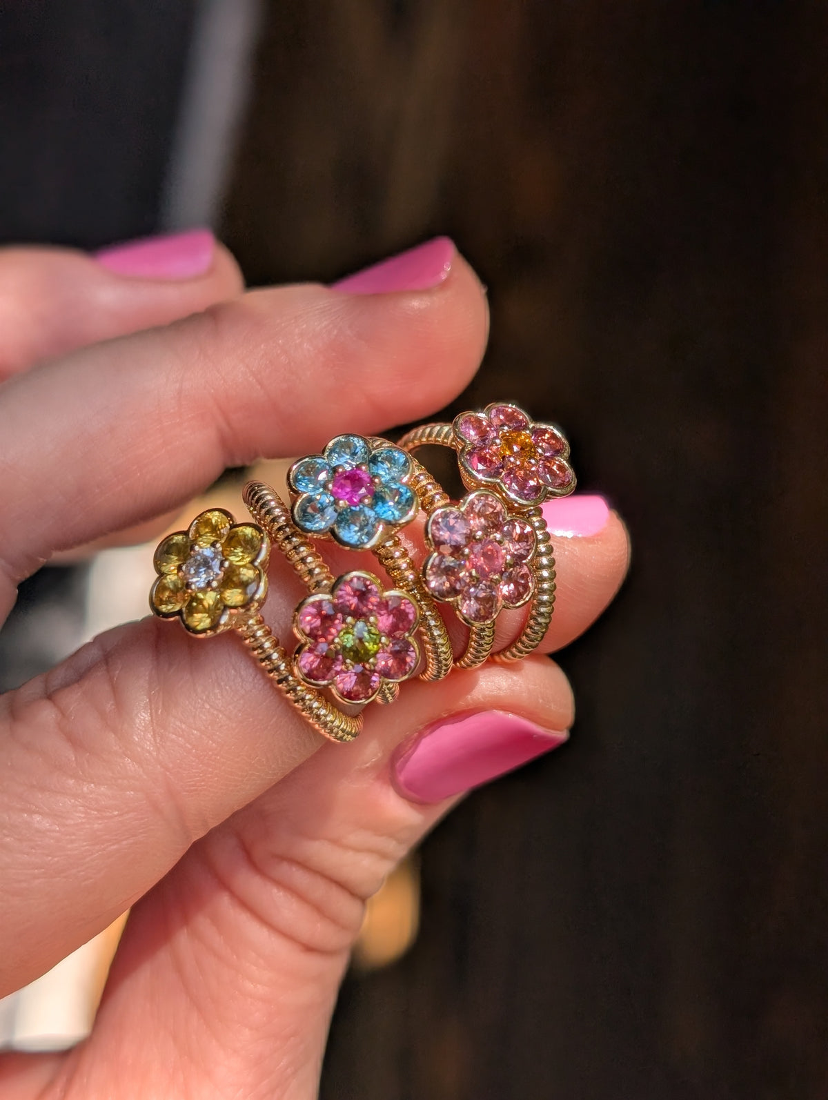 Five Blooms Medium Rings held in hand, showing the twisted gold bands