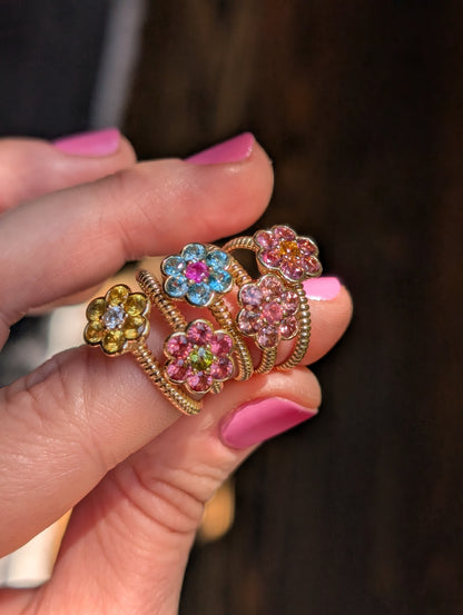 Five Blooms Medium Rings held in hand, showing the twisted gold bands