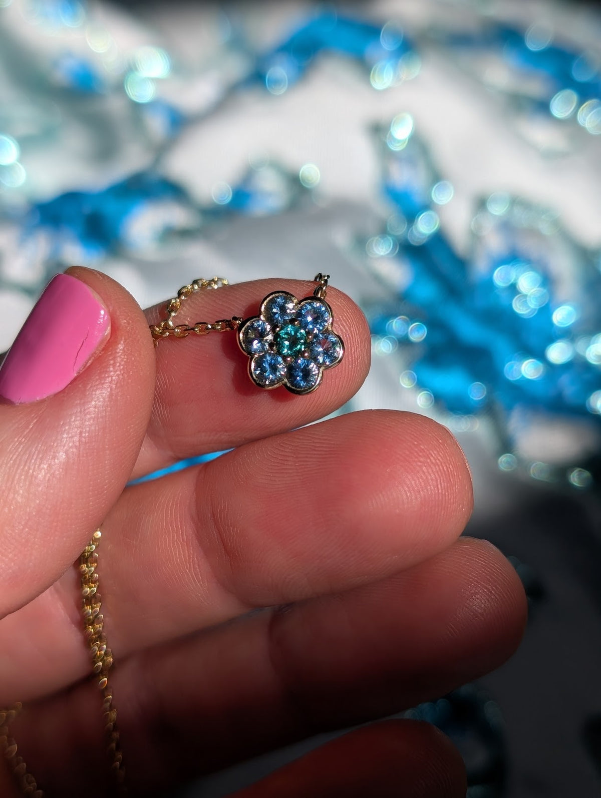 Small Blooms Pendant in aquamarine with tourmaline center, close-up held in hand