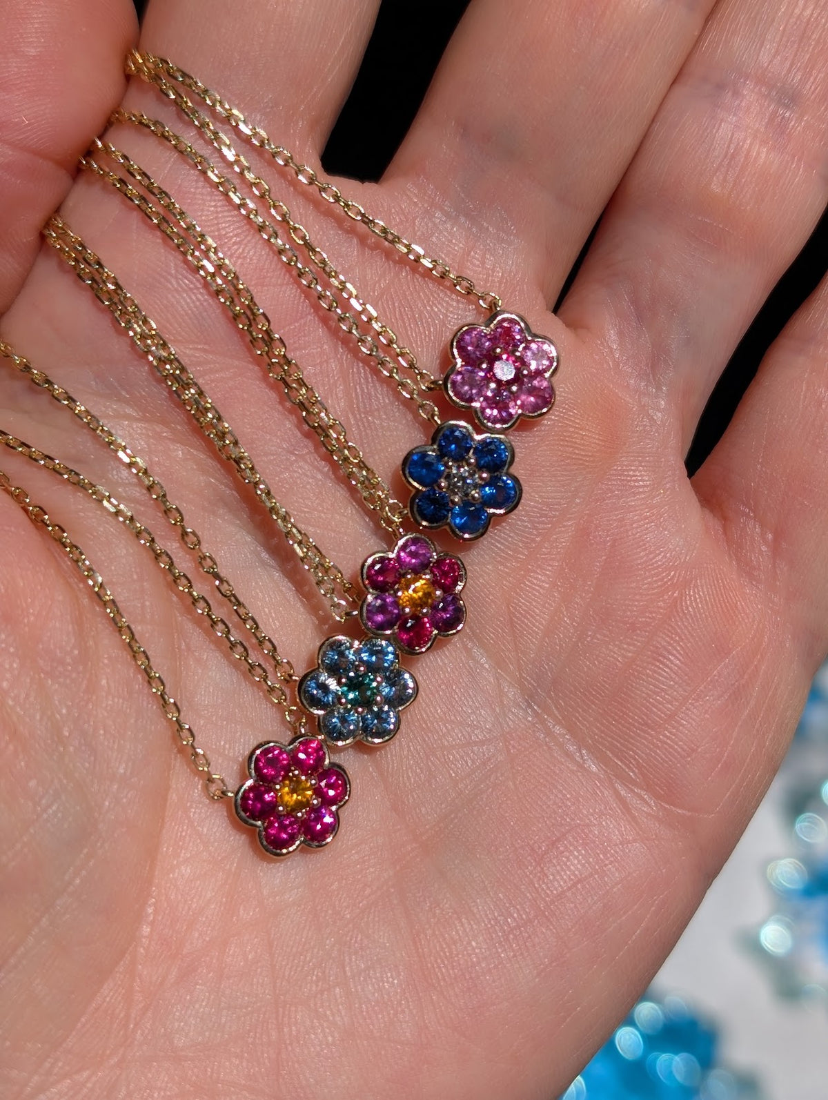 Five Small Blooms Pendants held in palm - Mehenge spinel and pink sapphire, blue sapphire and diamond, Burmese spinel with plum and spessartite garnet, aquamarine and tourmaline, Burmese spinel and spessartite garnet