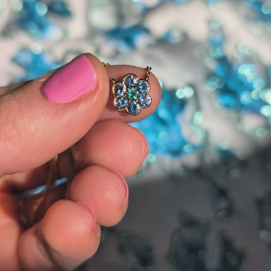 Video of the Small Blooms Pendant in aquamarine and tourmaline held between the fingers