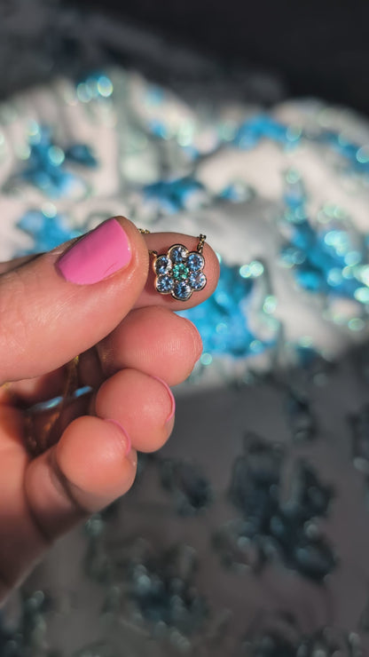 Video of the Small Blooms Pendant in aquamarine and tourmaline held between the fingers