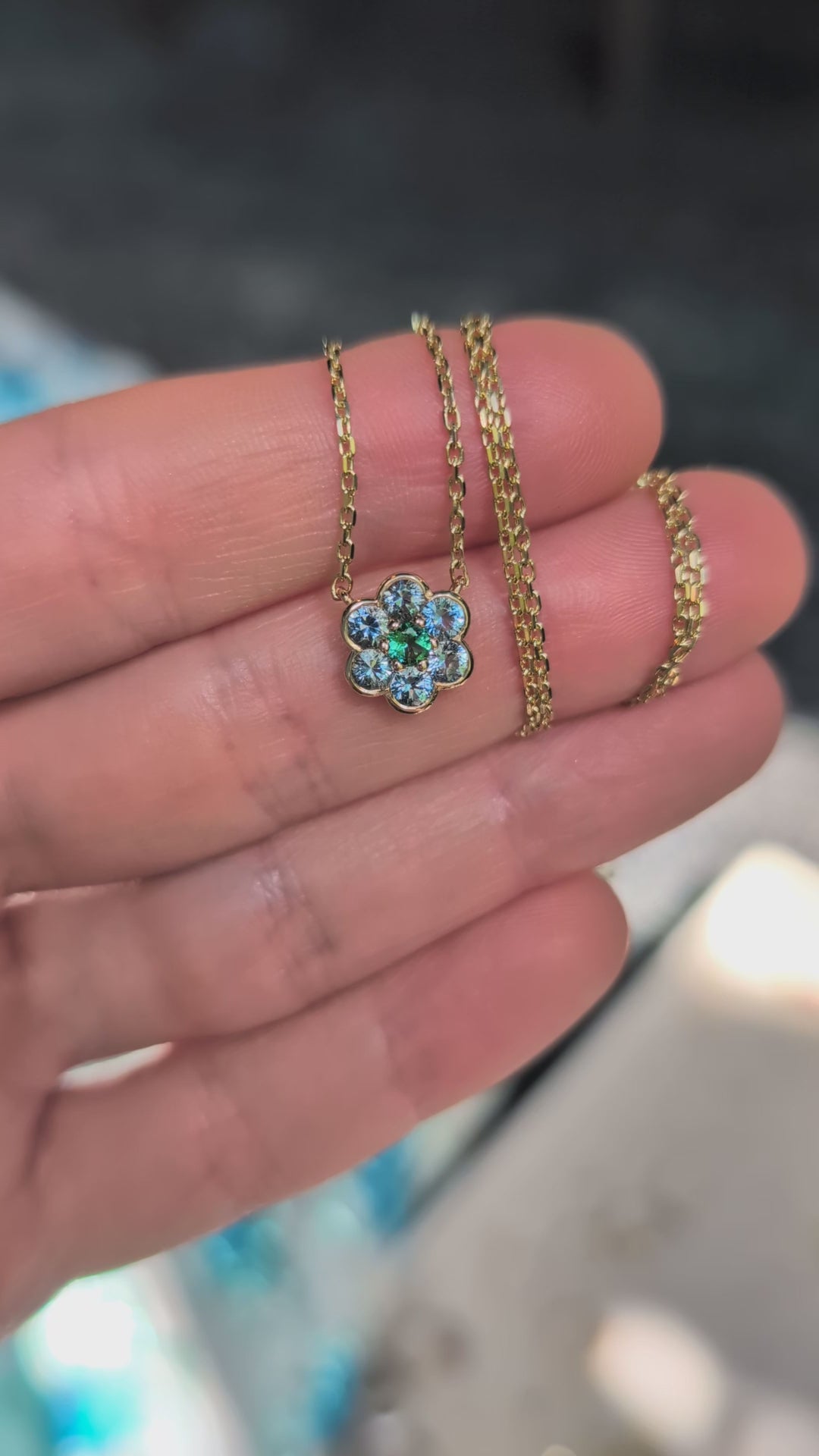 Video of the Small Blooms Pendant in aquamarine and tourmaline held in the palm