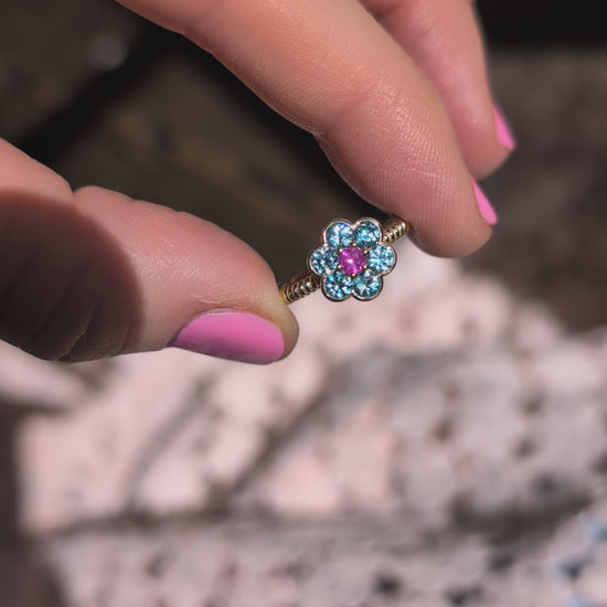 Video of the Blooms Medium Ring in blue zircon and pink ruby held in sunlight