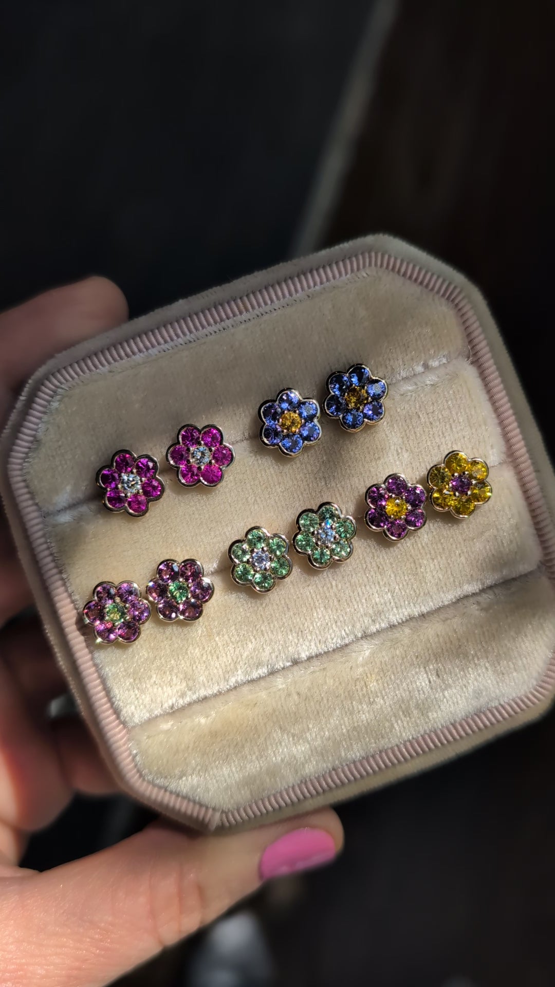 Video of five pairs of Blooms Stud Earrings in a velvet jewelry box in sunlight