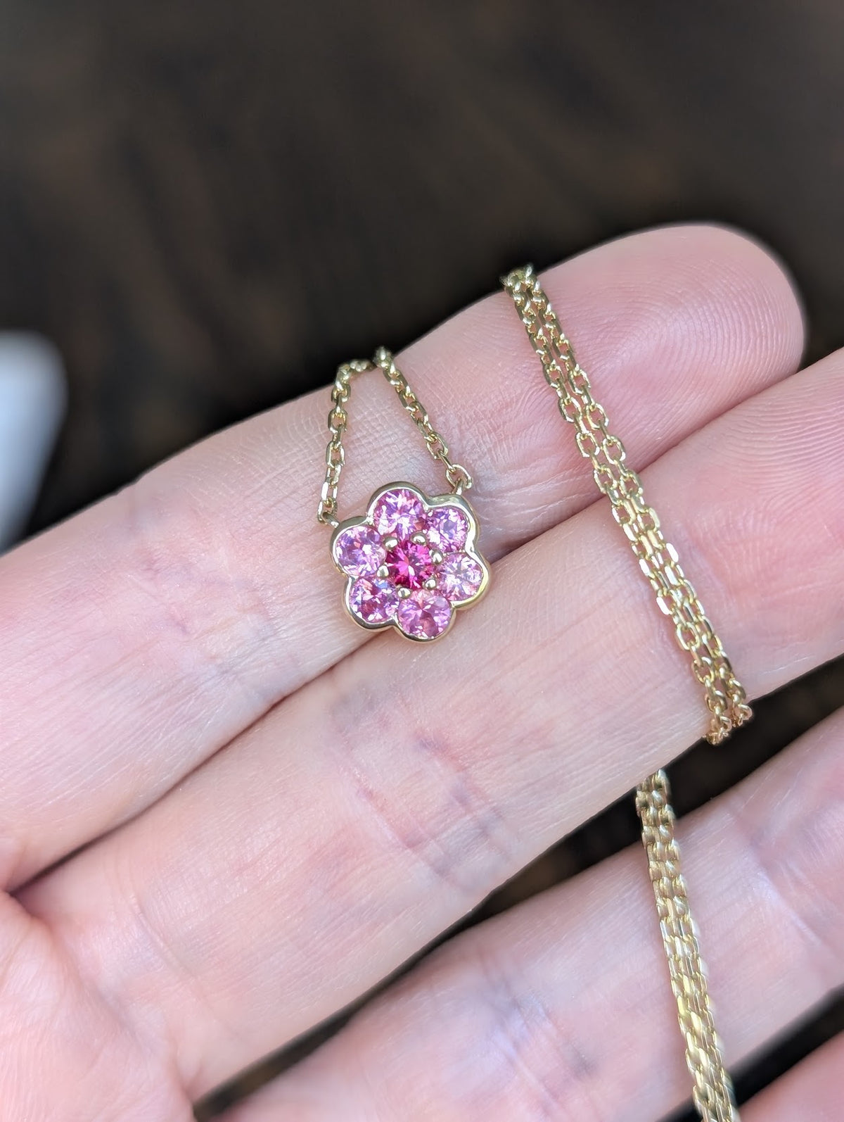Small Blooms Pendant in pink sapphire with Mehenge spinel center, close-up on fingers
