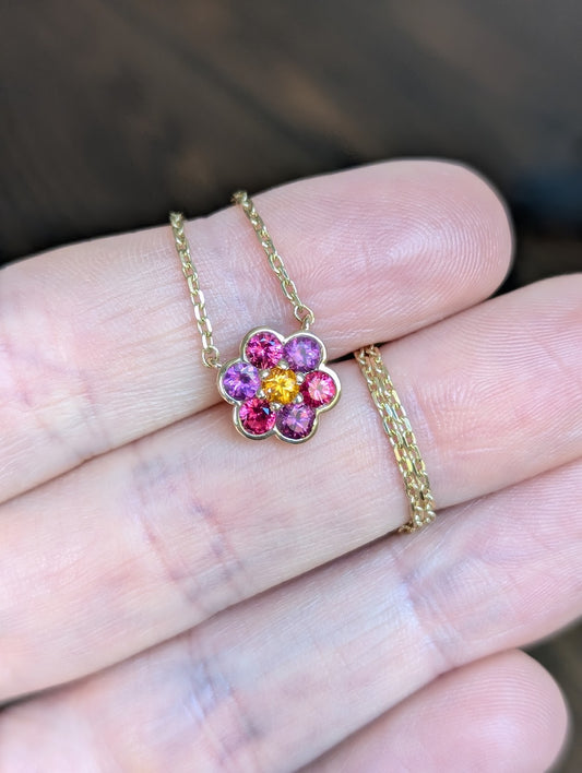 Small Blooms Pendant in Burmese spinel and plum garnet with spessartite garnet center, close-up on fingers